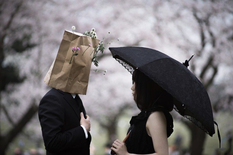 紙袋をかぶった男と傘をさした女